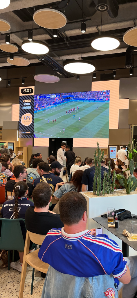 L'écran géant du foodcourt diffusant un match de foot