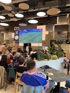 L'écran géant du foodcourt qui diffuse un match de foot